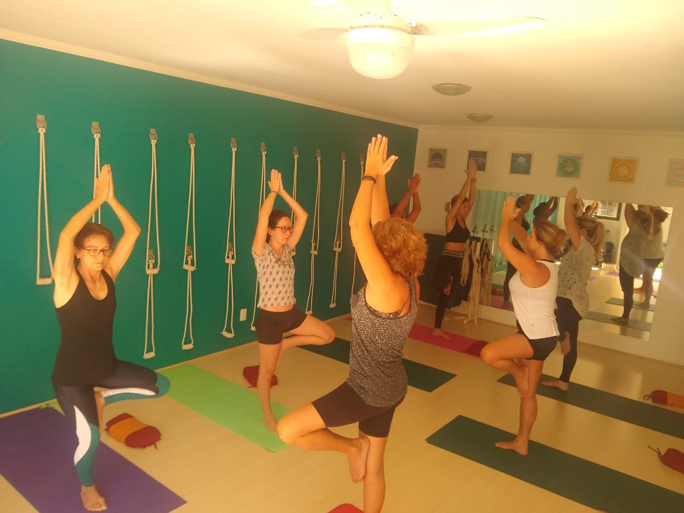 Turma de yoga reunida em aula presencial com tapetes coloridos, no espaço da Dani Pinotti em Imbituba.